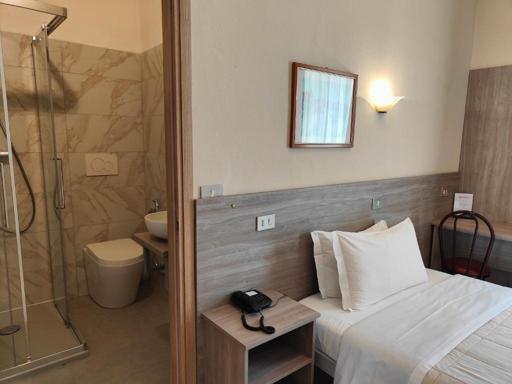 a bathroom with a bed and a shower and a phone at Hotel Romano in Turin