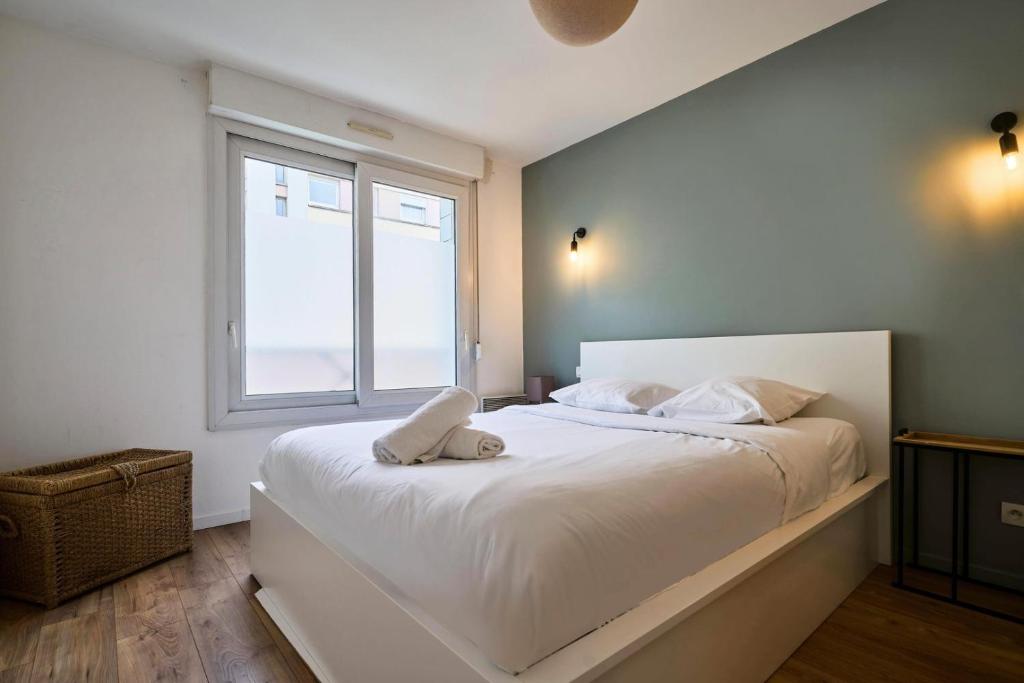a bedroom with a large white bed with a window at Apartment balconyparking space near train station in Lille
