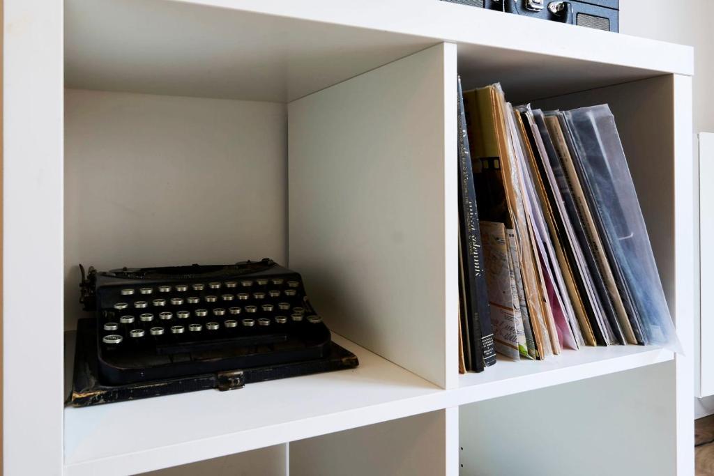 a white book shelf with an old typewriter in it at Apartment balconyparking space near train station in Lille