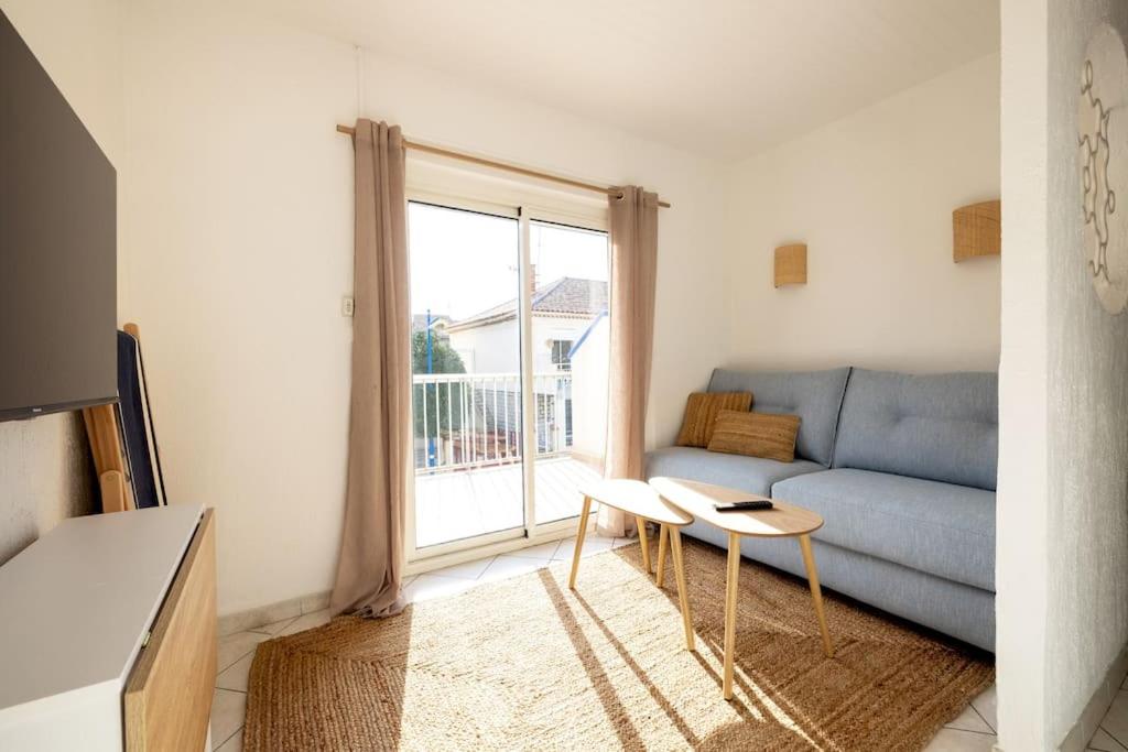 a living room with a blue couch and a window at Résidence Marie-Thérèse in Le Grau-du-Roi