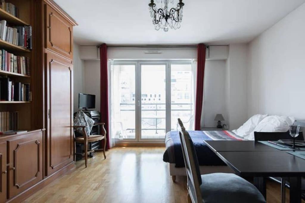- un salon avec une table à manger et une fenêtre dans l'établissement Le Cozy Appartement + balcon ensoleillé + Parking, à Paris