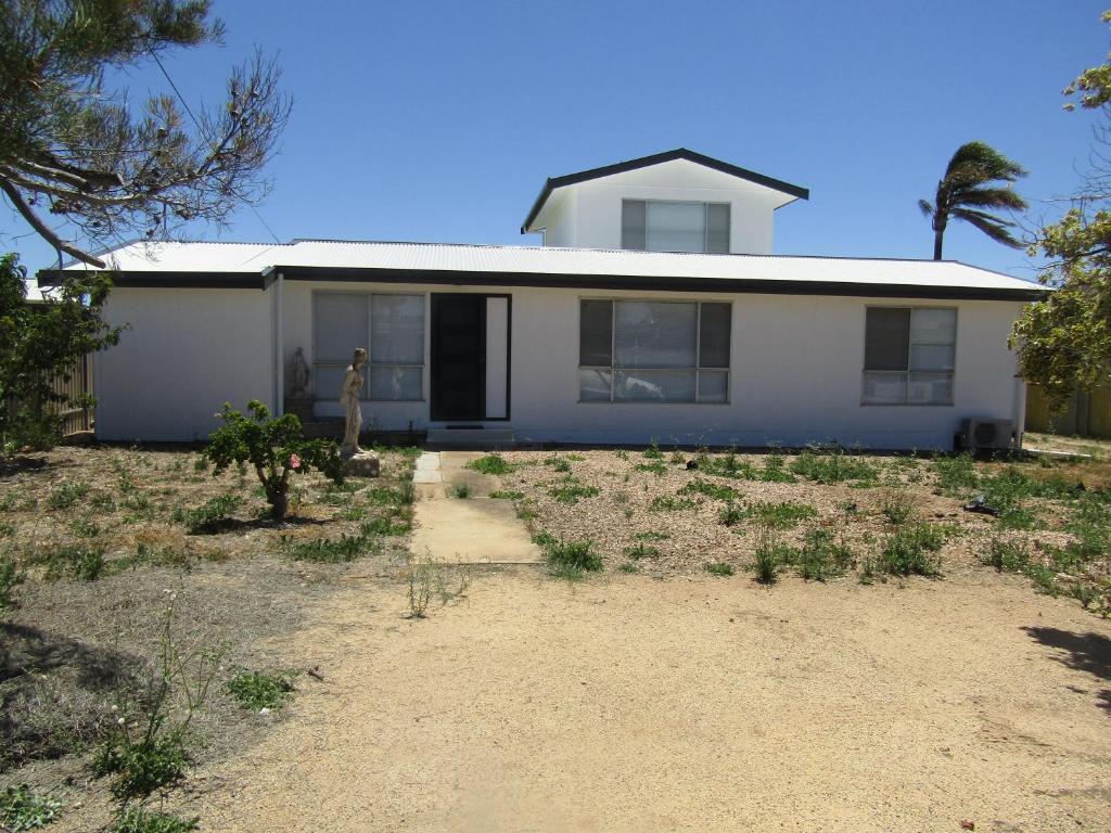 a white house with a palm tree in front of it at Seaview Retreat in Tiddy Widdy