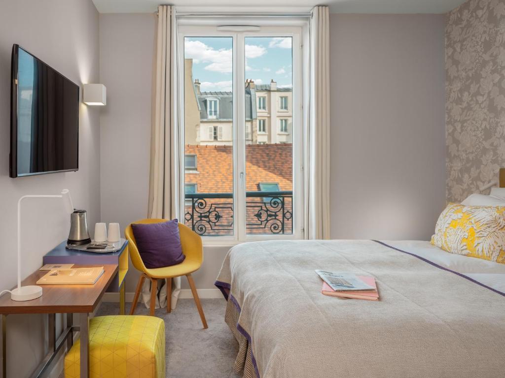 a hotel room with a bed and a desk and a window at Hotel Le Mareuil in Paris