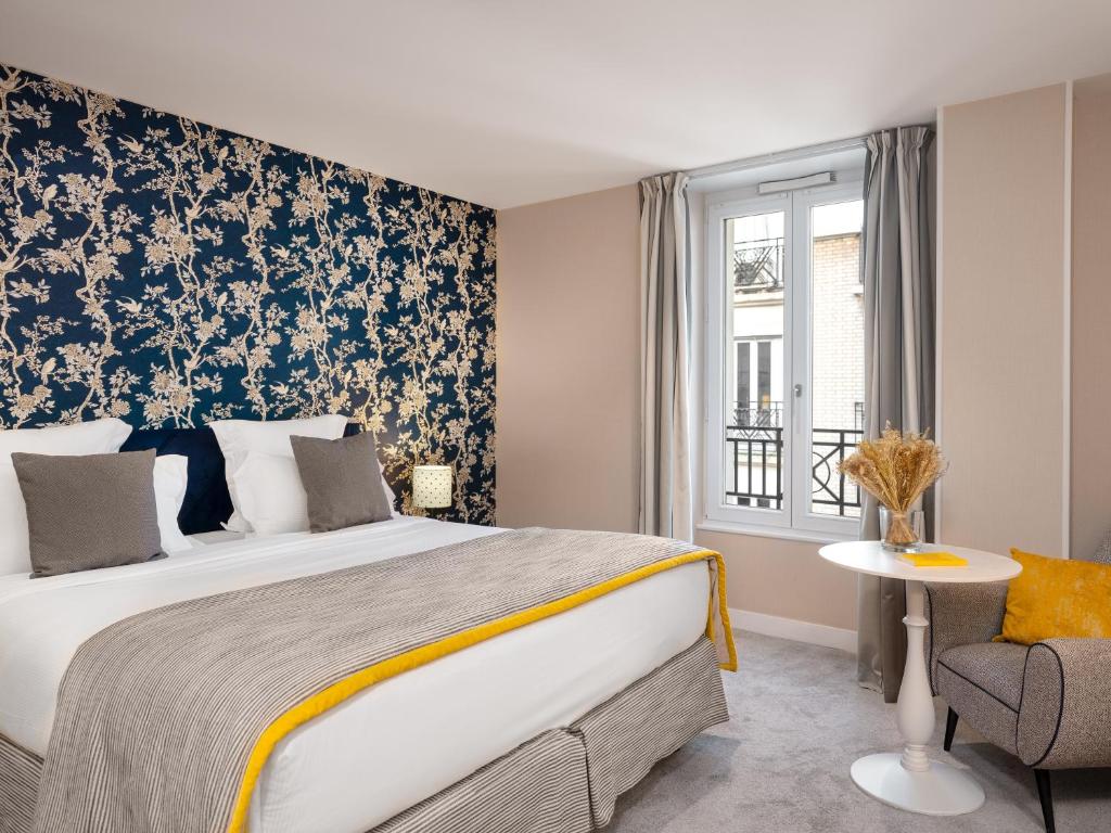 um quarto com uma cama grande e uma cadeira em Hotel Le Mareuil em Paris