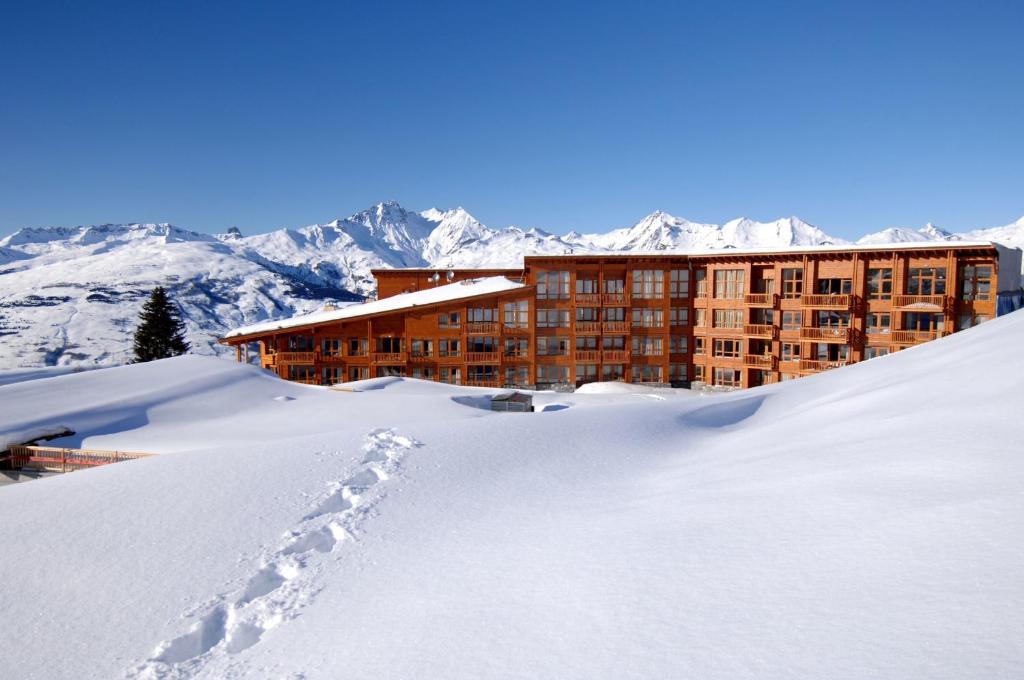 a hotel in the snow with mountains in the background at Appart'Hotel Prestige Odalys Eden in Arc 1800