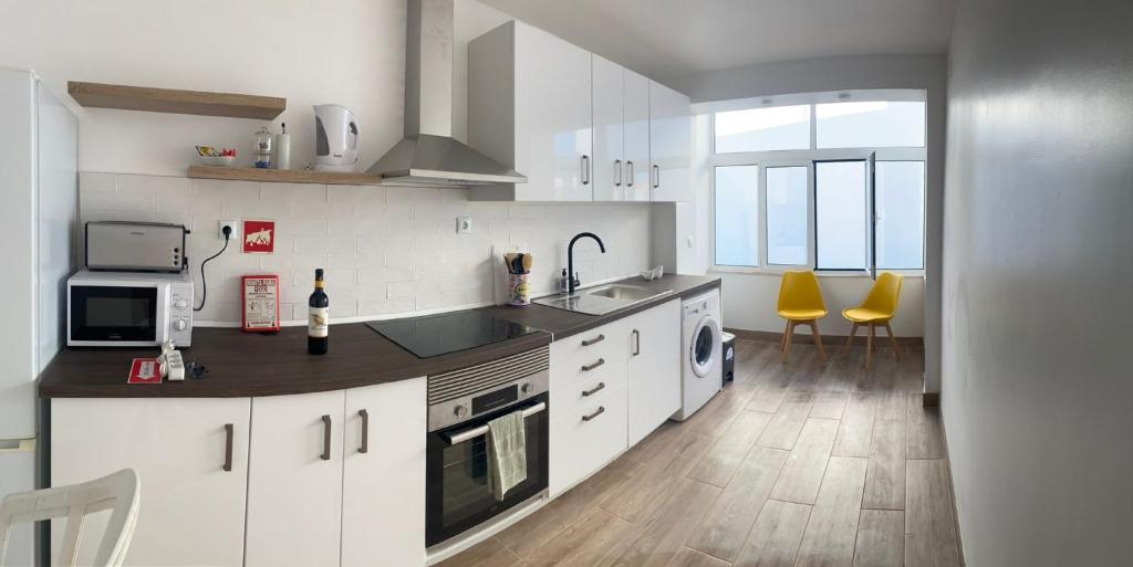 a kitchen with white cabinets and yellow chairs in it at SeaView Ericeira in Ericeira