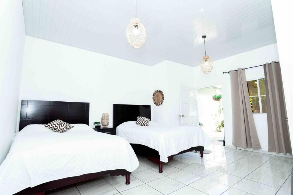 two beds in a white bedroom with white walls at Habitación Deluxe Tierra - Villa Valle Campo 