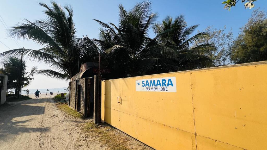 阿里巴格的住宿－Samara Sea View Resort，棕榈树海滩旁的黄色墙
