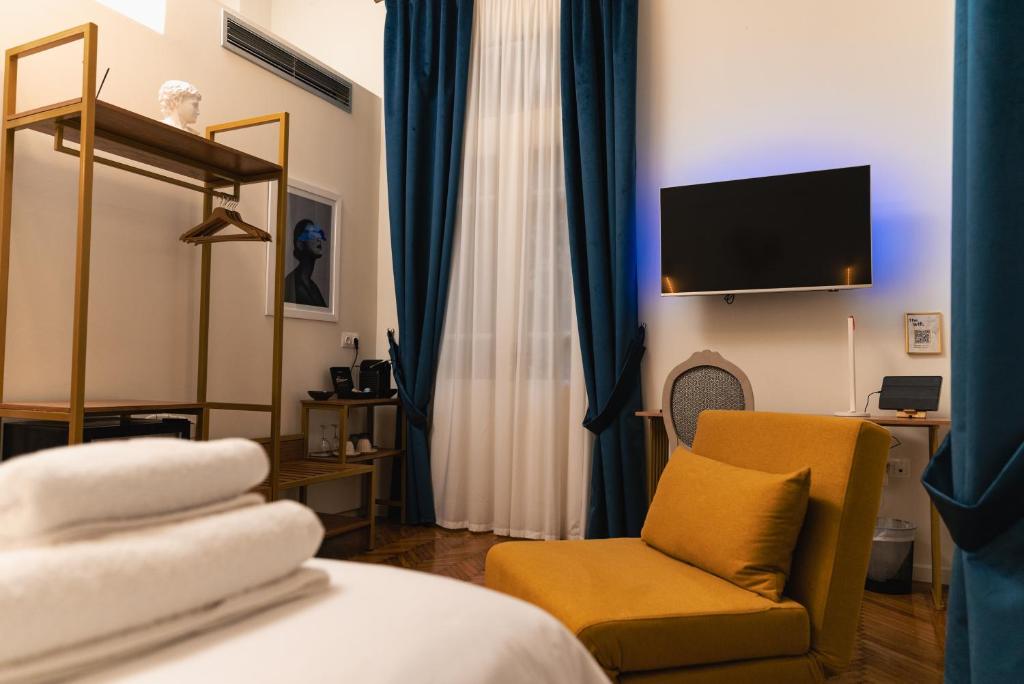 a hotel room with a bed and a chair and a television at Villa Clio, a Luxury Collection in Thessaloniki