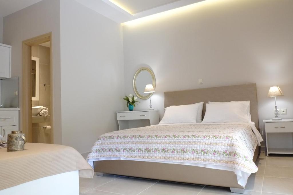 a white bedroom with a bed and a mirror at luxury studios ath in Limenas