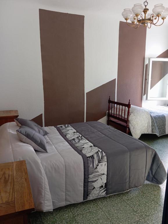 Un dormitorio con una cama grande y una lámpara de araña. en Casa de pueblo con piscina, en El Acebrón