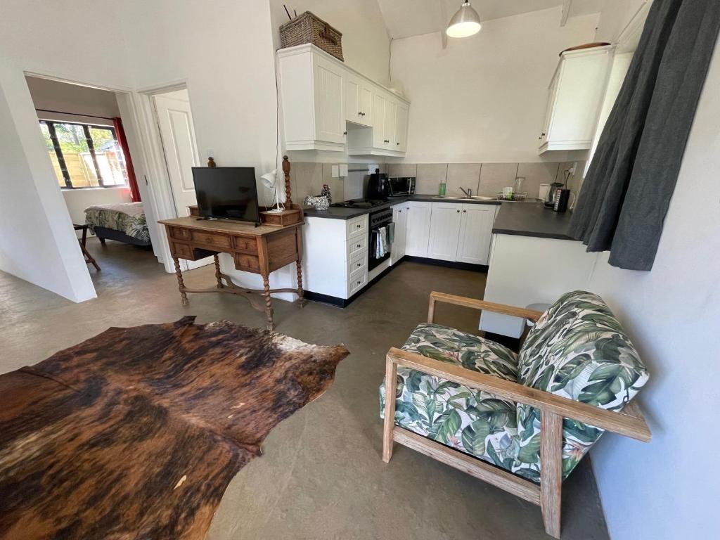a living room with a couch and a table and a kitchen at The Stables, Central Garden Cottage in Howick in Howick