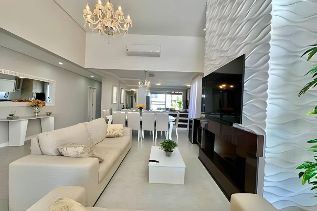 ein Wohnzimmer mit Sofa und Tisch in der Unterkunft Casa 4 Suítes com piscina Fundos Lago-Ilhas Resort in Capão da Canoa