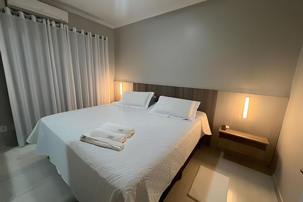 um quarto com uma cama branca e toalhas em Espaçoso & Aconchegante AP - Até 10 pessoas. em Santa Cruz do Sul