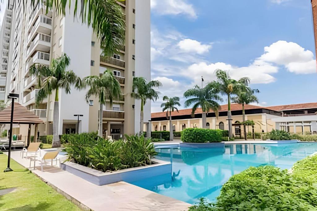 a swimming pool with palm trees and a building at Apartamento Espaçoso & Aconchegante - 3 quartos in Porto Alegre