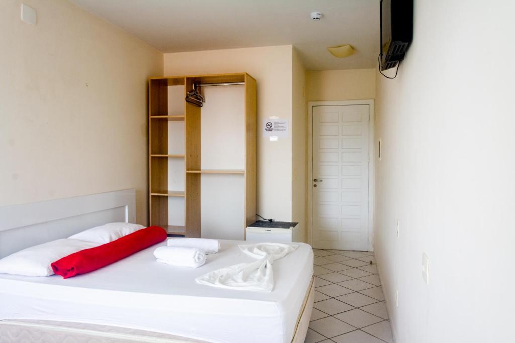 um quarto com uma cama branca e uma almofada vermelha em Hotel Lacala em Florianópolis