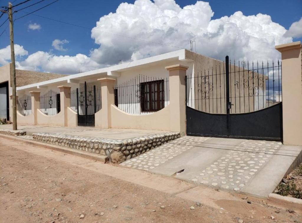ein weißes Haus mit einem schwarzen Tor auf einer Straße in der Unterkunft Casa Piedra Blanca in Cachí