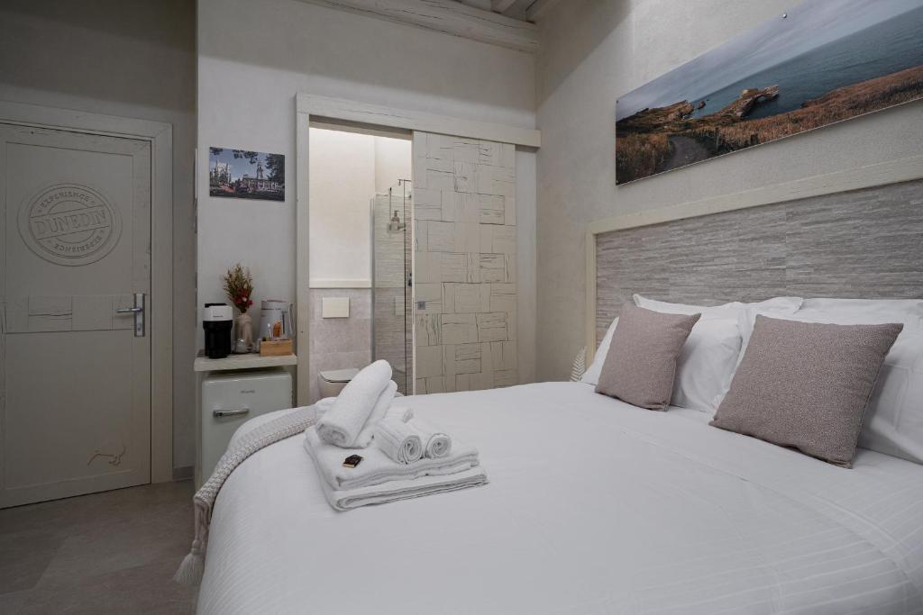 una camera da letto con un grande letto bianco con asciugamani di Nz Home a Foligno