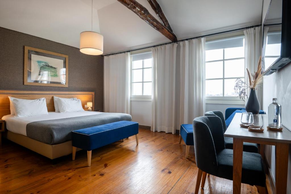 une chambre d'hôtel avec un lit, une table et des chaises dans l'établissement Santa Catarina FLH Suites, à Porto