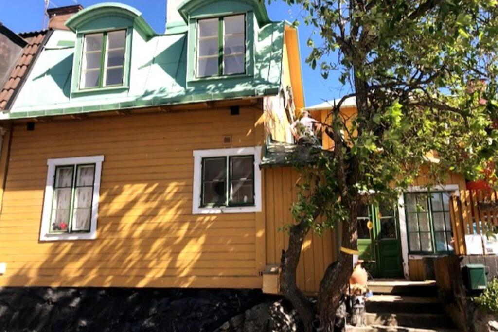 ein gelbes Haus mit grünem Dach in der Unterkunft Hus med ateljé i Centrala Vaxholm in Vaxholm