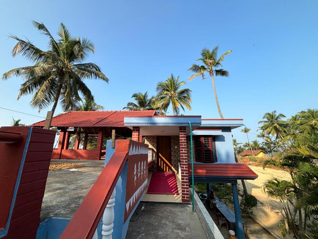 a house with a red roof and palm trees at Sea Shade in Udupi