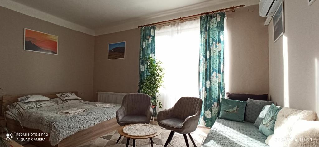 sypialnia z łóżkiem i dwoma krzesłami oraz oknem w obiekcie Karancs Apartman Salgótarján w mieście Salgótarján