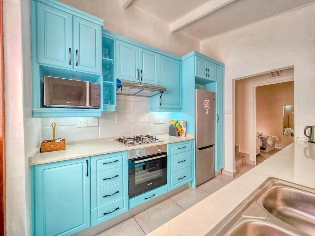 a large kitchen with blue cabinets and a sink at San Lameer 2401 by Top Destinations Rentals in Southbroom