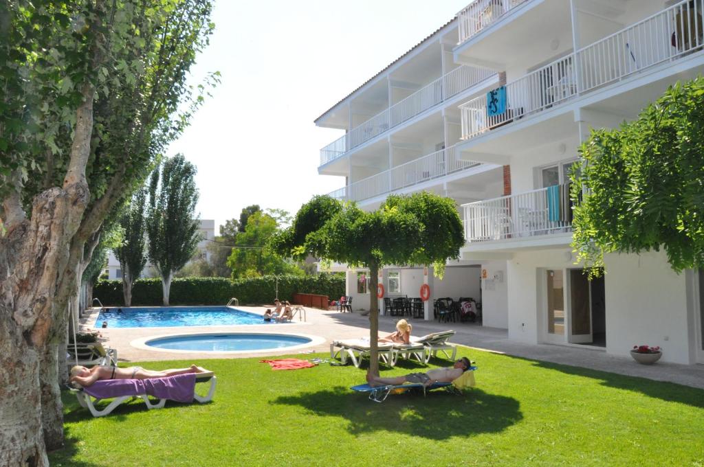 un patio de hotel con piscina y gente en el césped en Apartamentos Sunway Amapola en Sitges