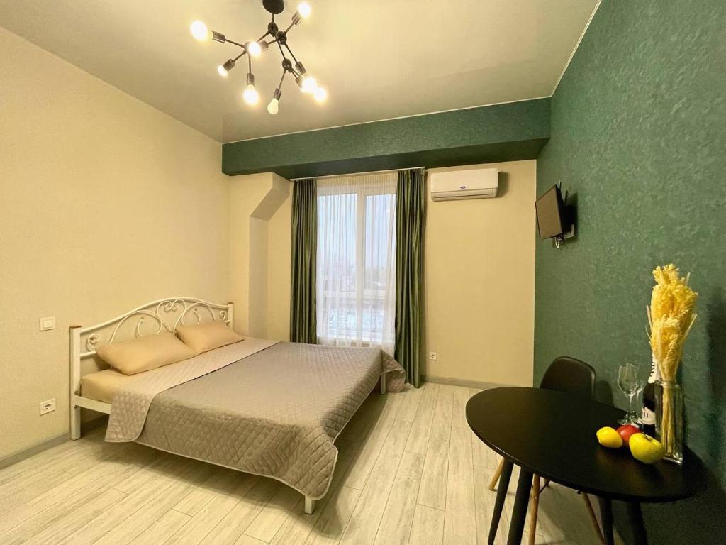 Schlafzimmer mit einem Bett, einem Tisch und einem Fenster in der Unterkunft Parkoviy kvartal in Kharkov