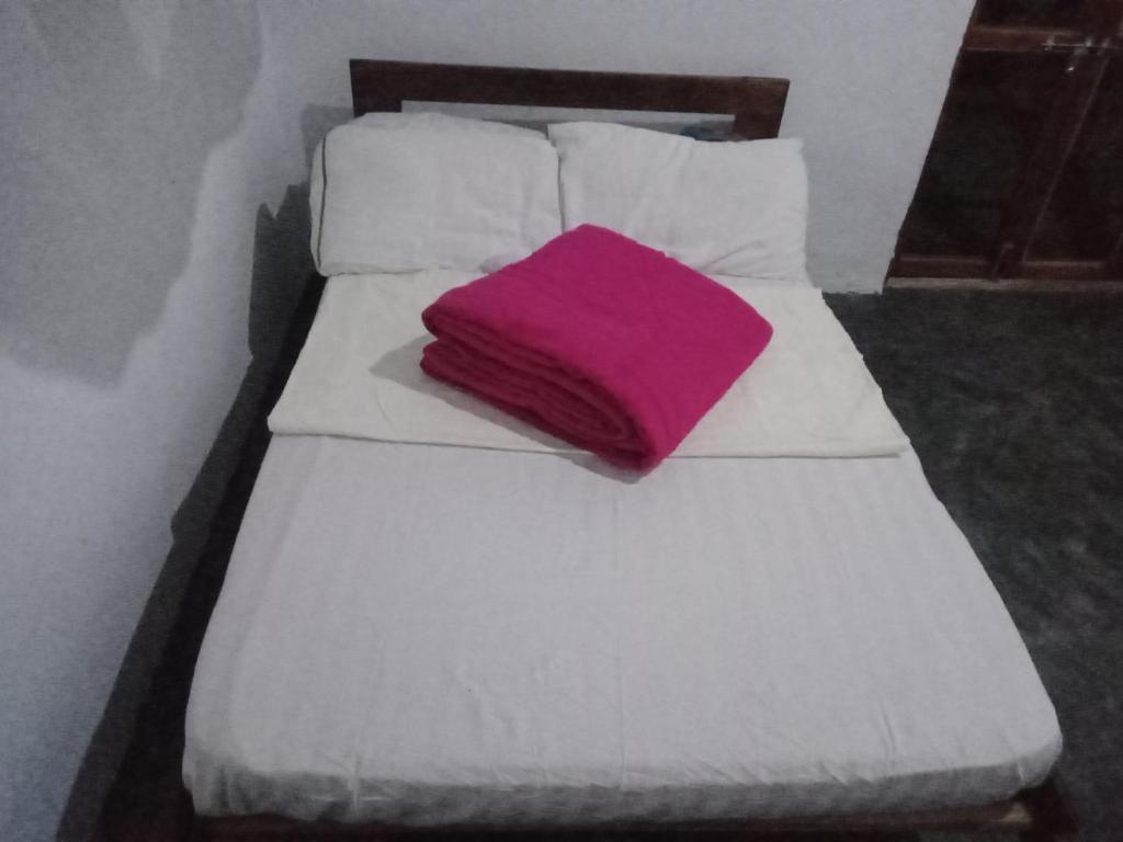 a white bed with a purple pillow on it at Wakanda cottage kibale in Fort Portal