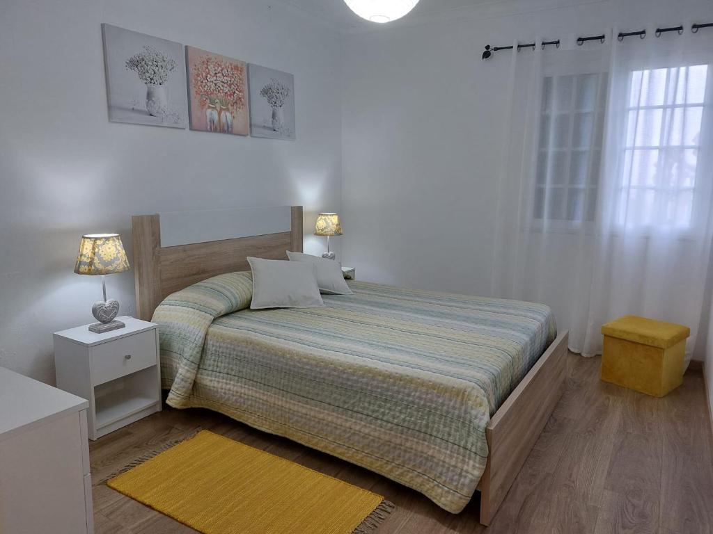 een slaapkamer met een bed en een geel tapijt bij Quinta do Sossego-Giestas in Ribeira Grande