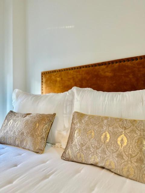 a bed with white pillows and a wooden headboard at Hospedería Nieves Centro in Chipiona