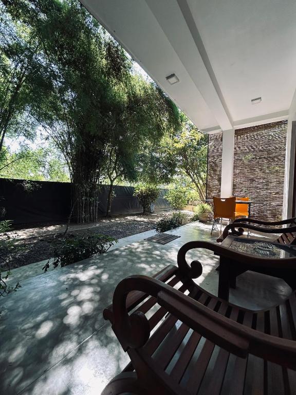 a porch with a bench and a table and trees at Green Corridor - Ahangama in Ahangama