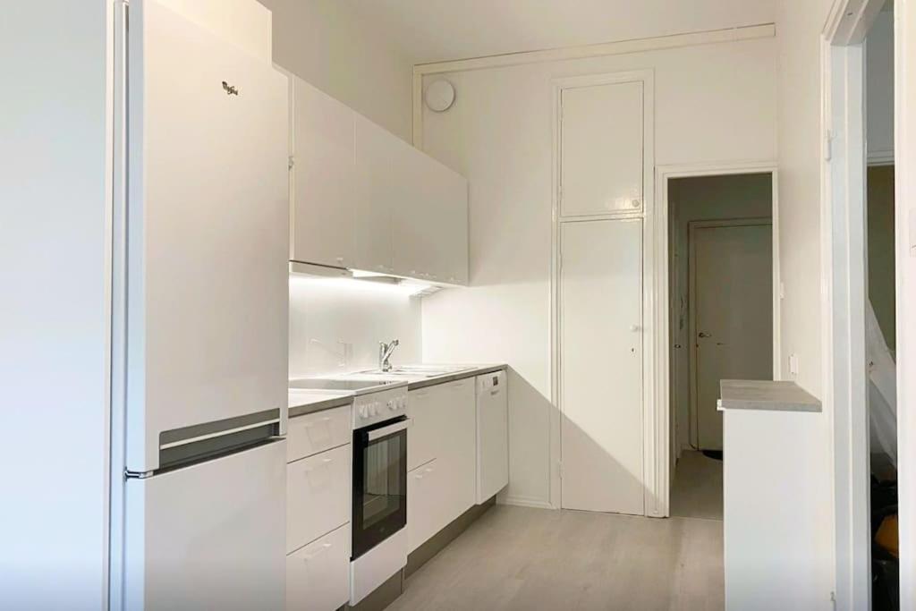 La cuisine blanche est équipée d'un évier et d'un réfrigérateur. dans l'établissement Moderni siisti Studio koti jossa modernit kalusteet, à Helsinki