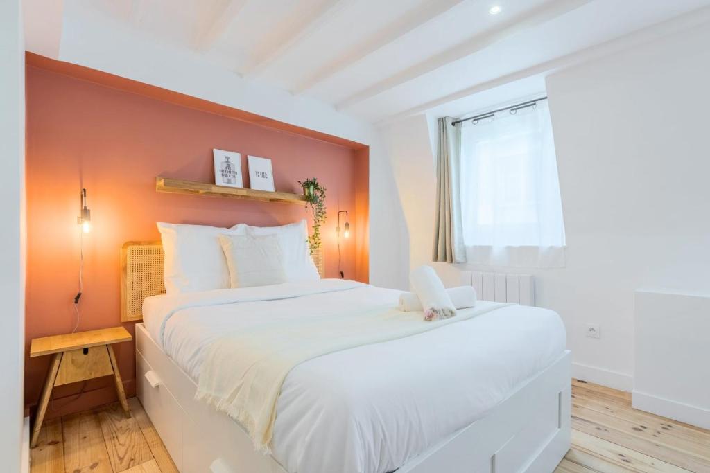 - une chambre avec un grand lit blanc et un mur orange dans l'établissement Lille center bright and functional studio, à Lille