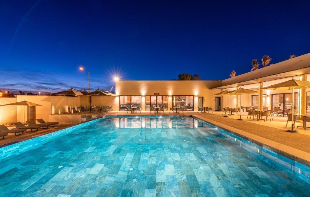a large swimming pool in front of a house at night at Kenzi Rissani in Er Rachidia