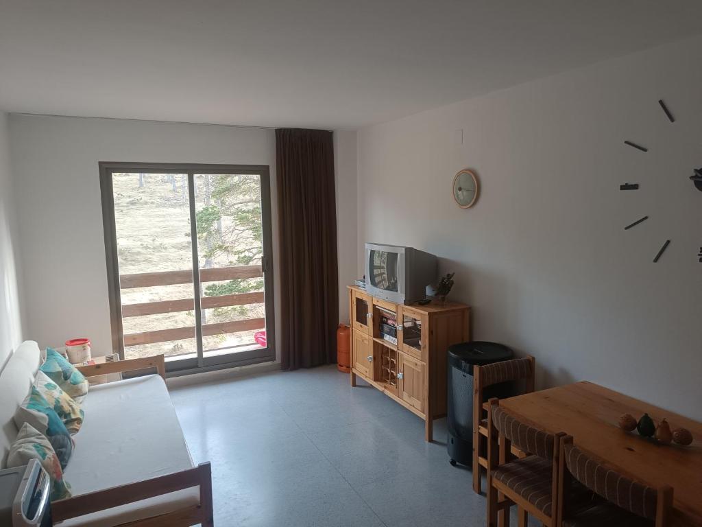 ein Wohnzimmer mit einem Tisch und einer Uhr an der Wand in der Unterkunft Apartamento a pie de pistas Port del Comte in La Coma i la Pedra