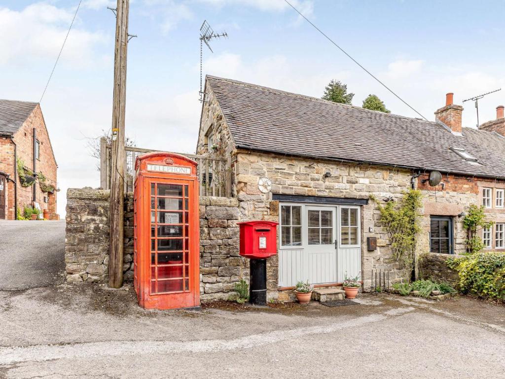 an old red telephone booth in front of a stone cottage at 1 Bed in Hognaston PK927 in Hognaston