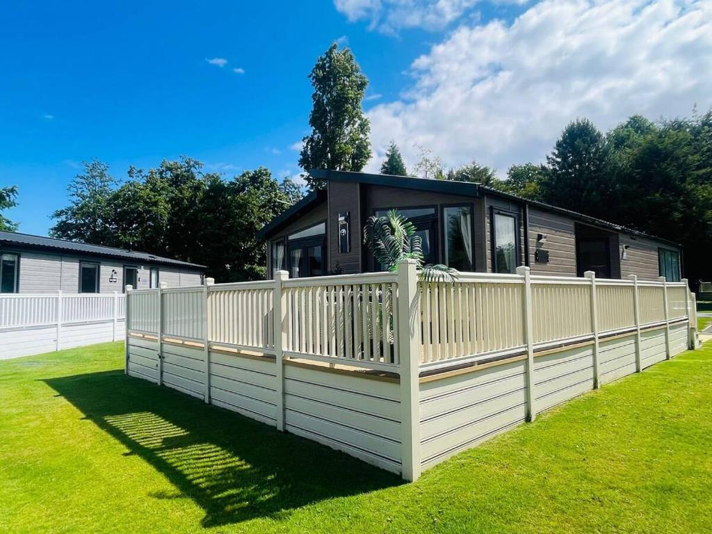 a house with a white fence in a yard at Enzo's Lodge with Hot Tub in York
