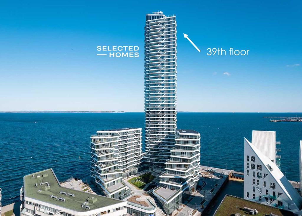 a tall building with a sign on it next to the ocean at Penthouse paradise on 39th floor in Aarhus