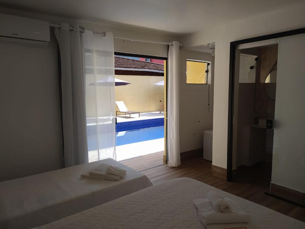 a bedroom with a bed and a view of a pool at Pousada Villa Encanto in Juquei