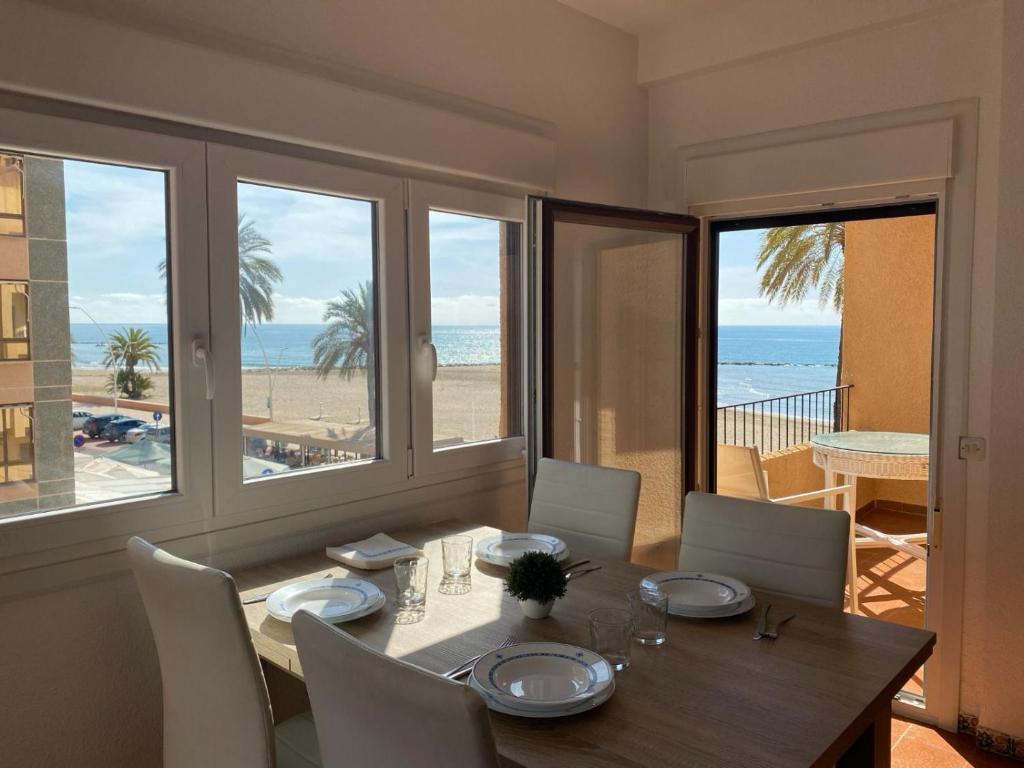 ein Esszimmer mit einem Tisch und Blick auf den Strand in der Unterkunft Apartamento frente al Mediterraneo in Torreblanca