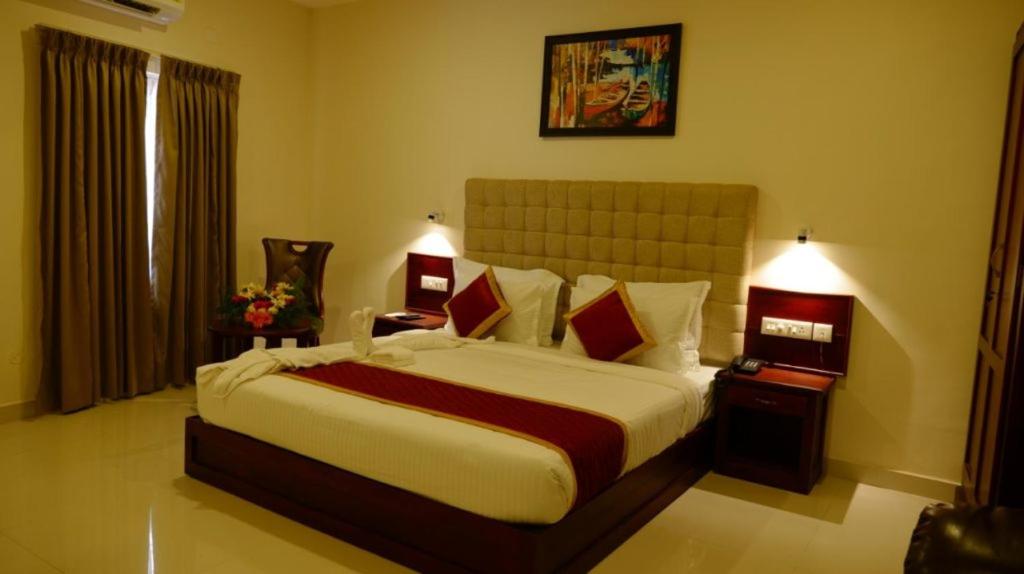 a bedroom with a large bed and two night stands at HOTEL PALAZHI in Pattanapuram