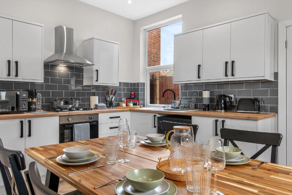 a kitchen with a wooden table and white cabinets at Whitehill House - 3-Bed Home from Home, Sleeps 7, Great for Groups & Workers, FREE Parking & Netflix in Whiston