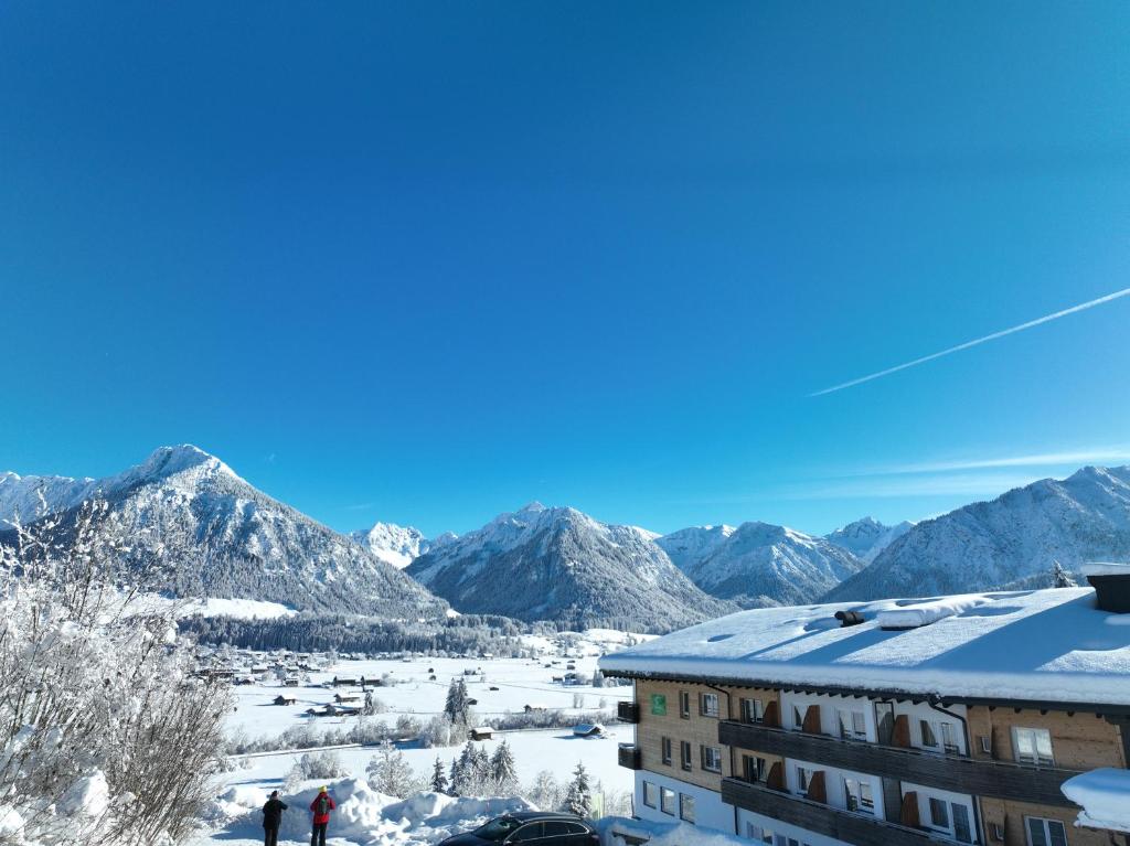 a view of the mountains from a building in the snow at Naturhotel Waldesruhe Oberstdorf in Oberstdorf