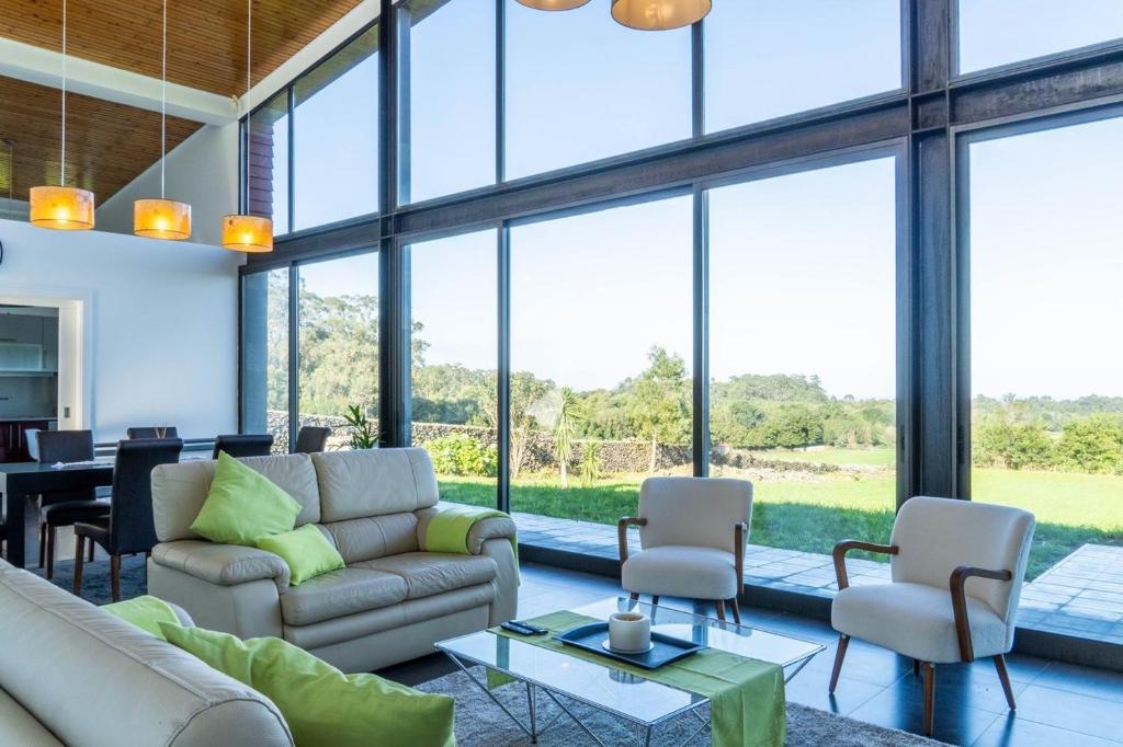 a living room with a couch and chairs and windows at Batalha Golf Villa in Pico da Pedra