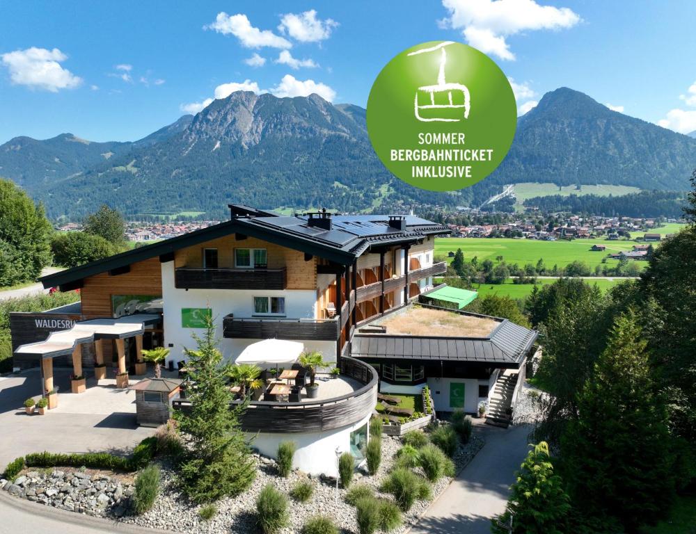 une image d'une maison avec une montagne en arrière-plan dans l'établissement Naturhotel Café Waldesruhe, à Oberstdorf