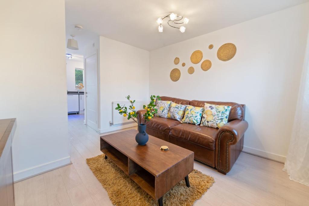 a living room with a brown leather couch and a table at Luxury house close to city center sleeps 6 with free parking in Leicester