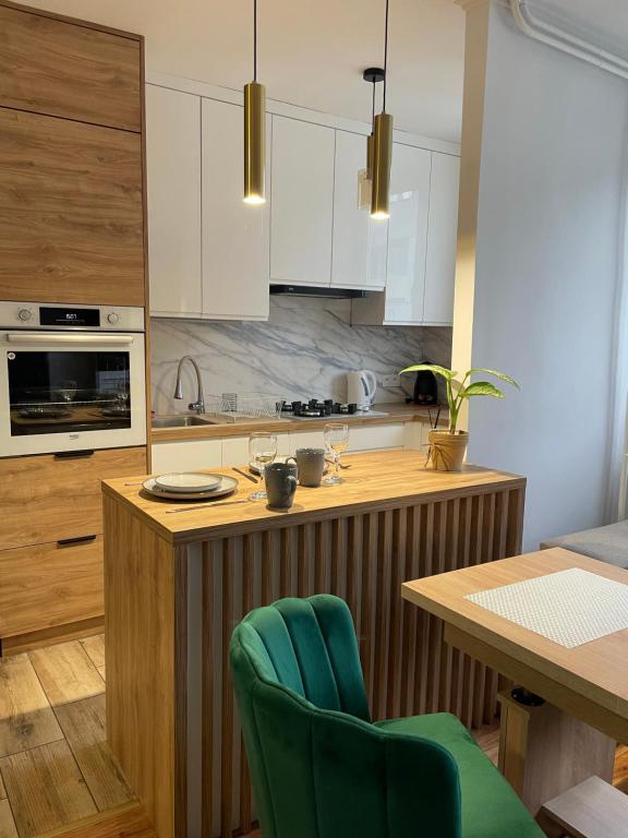 eine Küche mit weißen Schränken und eine Holzterrasse mit grünen Stühlen in der Unterkunft Apartament Żwakowska in Tychy