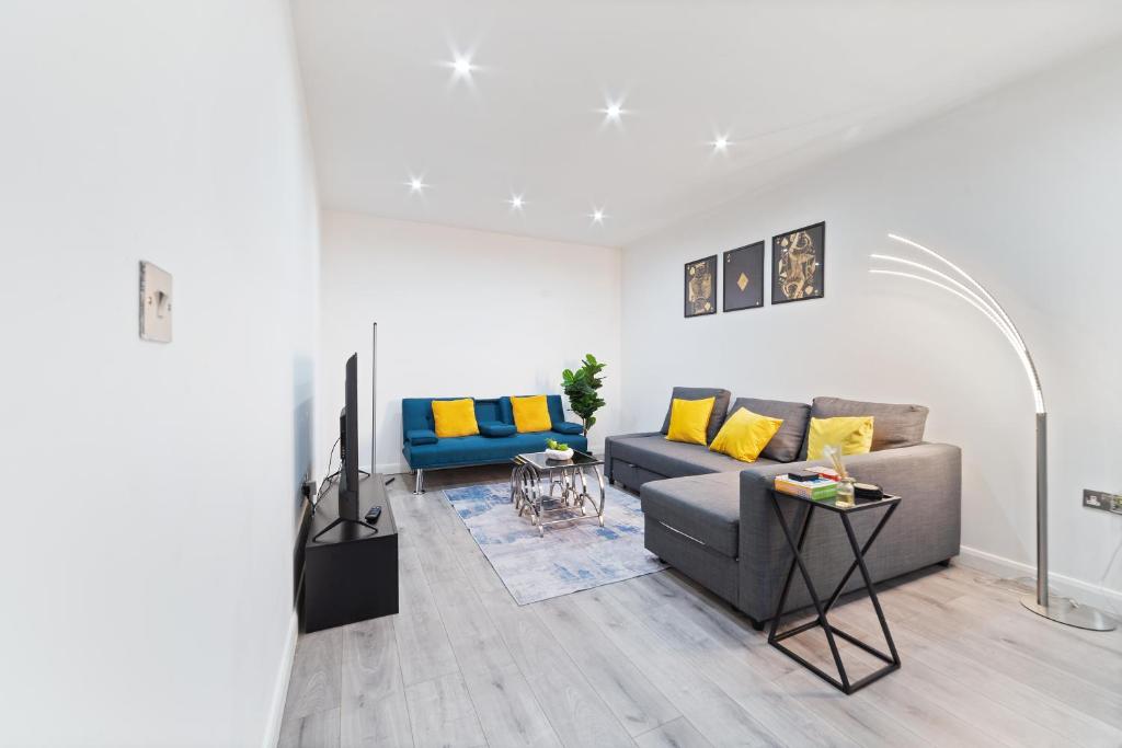 a living room with a gray couch and yellow pillows at Modern Apartment with Pool table in Leicester